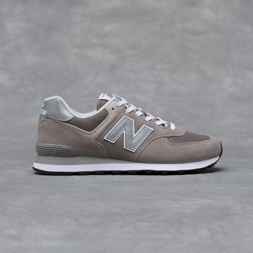 A grey New Balance 574 sneaker on a grey studio backdrop.