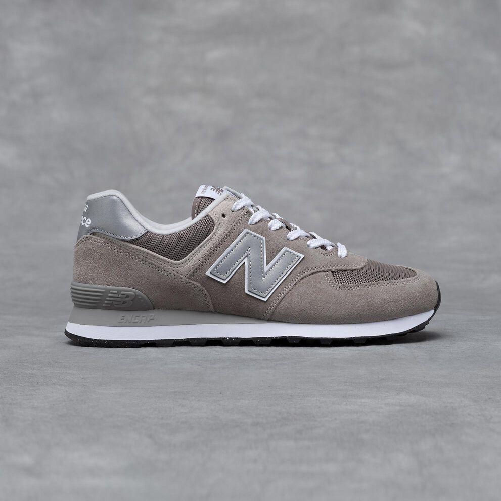 A grey New Balance 574 sneaker on a grey studio backdrop.