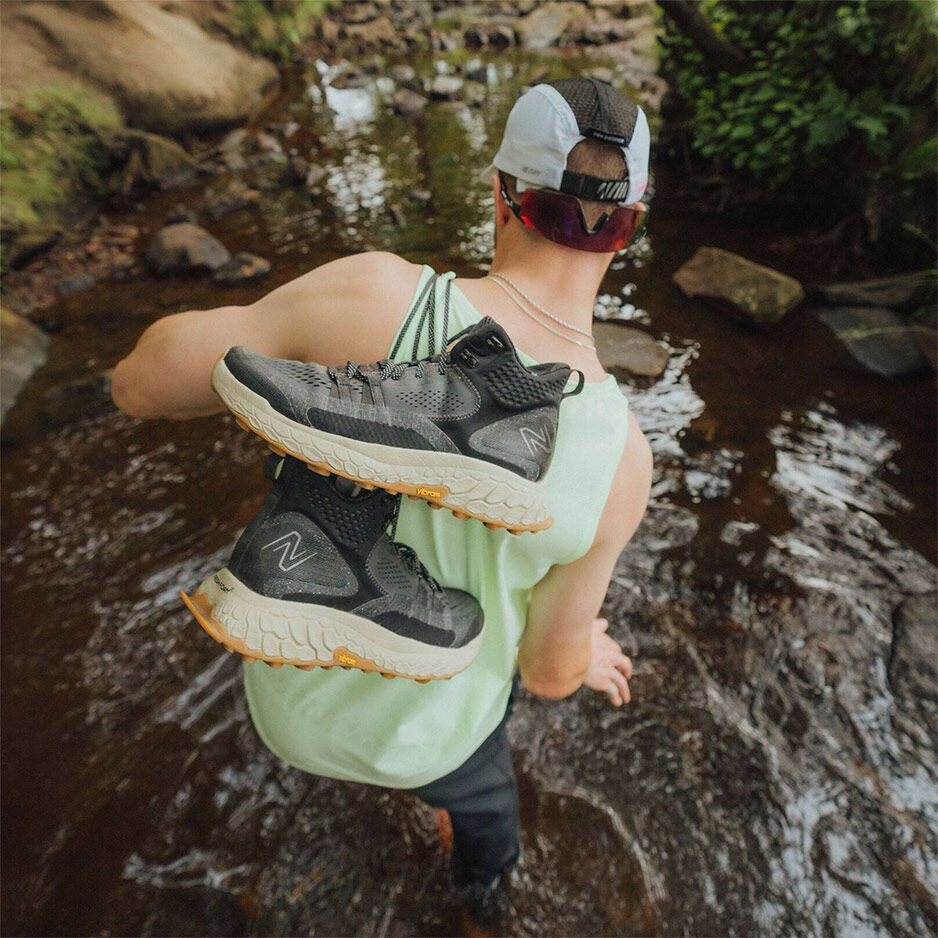 Human walking through water carrying shoes