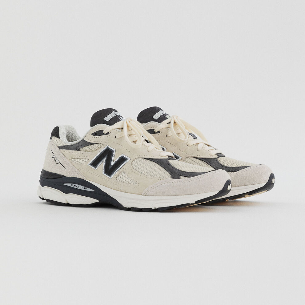 A pair of white 990v3 pointing to the right from the upcoming MADE Seasonal collection on a grey background.